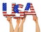 People arms hands holding up wooden letter lettering forming words united states of america USA stars spangled banner national