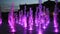 People bathe in an illuminated purple fountain in Mykolaiv at night