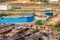 People bathing at a common handpump well tank in a slum with the ramshakle houses near them with modern buildings in the distance