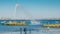 People on a beach near Lisbon with a geyser overlooking the iconic 25 April Bridge and Rei Cristo statue