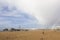 people on beach near scheveningen pier with cloudy sky and rainbow