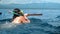 People on boat sail behind masked dolphin family Stenellalongirostris submerged in open, clear sea