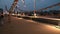 People on car bridge over river in the evening.