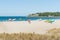 People carrying boards and surf skis across scenic beach to sea