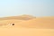 People chasing around sand dunes on a quad bike