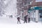 People on a city street covered in snow during heavy snowfall storm in Madrid