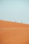 People climbing Erg Chebbi dunes in Sahara Desert, Merzouga, Morocco