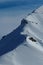 People climbing the ridge of a snowy mountain in Italian Alpes, with snowshoes or ski