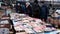 People crowd in a flea market. Men and women choose used books.