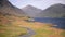 People cycling on a road by the lake towards the mountains of the England Lake District -