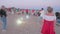 People dance on the beach during open air concert of man playing violin. Summer activities