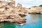People diving from the cliff, sunbathing, swimming in crystal clear sea water on the rocky beach Torre Sant Andrea with rocks,