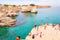 People diving from the cliff, sunbathing, swimming in crystal clear sea water on the rocky beach Torre Sant Andrea with rocks,