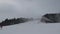 People do skiing on the mountainside. Skiers go down the snow slope. Out of focus background is the mountain slope with the descen