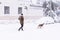 People with dog walking on a city street covered in snow during heavy snowfall storm in Madrid