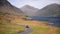 People driving on a road by the lake towards the mountains of the England Lake District -