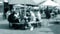 People eat sitting at tables with umbrellas covering on sunny day on town.