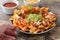 People eating mexican nachos with beef, guacamole, cheese sauce, peppers, tomato and onion in plate on wood