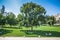 People are enjoying sunny day on grass in Burggarten park in vienna. They are sitting on neat lawn in the shadows of trees