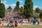 People enjoying sunny summer day on meadow in crowded Park Maue