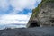 People explore the interesting basalt rock volcanic formations along the black sand beach near Vik,