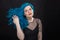 People and fashion concept - Young and attractive woman with black lipstick and blue hair posing over black background