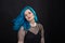 People and fashion concept - Young and attractive woman with black lipstick and blue hair posing over black background