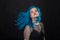 People and fashion concept - Young and attractive woman with black lipstick and blue hair posing over black background