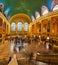 People fill iconic Grand Central Station wide panorama by stairs in New York City