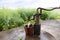 People filling bucket with water from Hand pump in hand-dig well in shallow aquifers in villages in countryside in China. Rapeseed