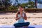 People, fitness, music and healthy lifestyle concept - asian girl meditating listening the music with headset on tropical beach