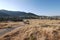 People go from the steppe yellow to the dry grass of the hills into a small village