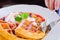 People hand used silver spoon and fork to eat Sweet waffles with strawberries sauce vanilla ice cream and fresh fruit on white pla