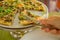 People hands taking slices of pizza. Table with pizza in a restaurant. Pizza and hands close up on a green