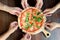 People Hands Taking Slices of Salmon Pizza with rocket and tomato..High angle friend group hands grabbing a slice of pizza..Family