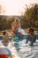 People having fun with water guns in pool at summer vacation