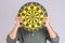People holding yellow Dartboard and hide his face. Studio shot  on grey