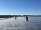 People ice skating on a frozen lake towards IJlst