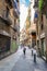 People inside an alleyway/ narrow brick street of shops and homes in Barcelona