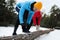 People lacing sneakers on log in winter forest. Outdoors sports exercises