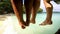 People, legs and dangle on pier, vacation and lake for adventure, fun and relaxing. Closeup, couple of friends on