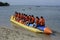 People with life jacket having joy ride on long banana boat on sandy beach