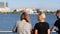 People look at flying seagulls on modern city embankment