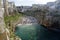 People on lovely beach Lama Monachile with dramatic view of cliffs with caves rising from Adriatic sea in Polignano a Mare