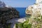 People on lovely beach Lama Monachile with dramatic view of cliffs with caves rising from Adriatic sea in Polignano a Mare