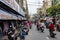 People on motorbikes on the street with small fabric stores on the sidewalk