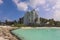 People near the White Sandy Beach with the Palm Trees and Hotel Building on the Maldivian Paradise Island