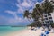 People near the White Sandy Beach with the Palm Trees and Hotel Building on the Maldivian Paradise Island