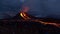 People observing recently erupted volcano at Fagradalsfjall with lava ejection, flowing streams of glowing lava and fumes.