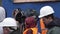 People in orange uniform with helmets and videocameras gathered outside.